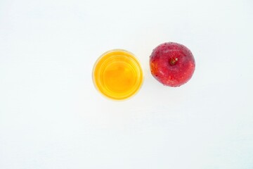 Apple juice in a glass and ripe fruit on a cream-colored table