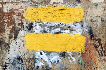 Abstract Vintage old damaged wall with cracks, scratches and scraps of paper, painted with yellow paint. Oncrete, weathered with cracks and scratches. Landscape style. Grungy Concrete Surface.