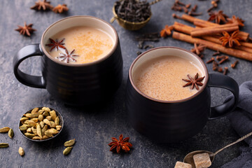 Obraz na płótnie Canvas Indian masala tea with milk and spices in mug. Grey background. Close up.