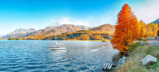 Picturesque autumn views of Sils Lake (Silsersee) with small white yacht