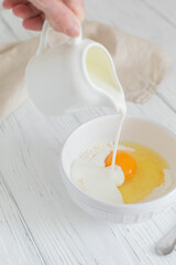 Ingredients for making pancakes, flour, milk pouring, egg, top view