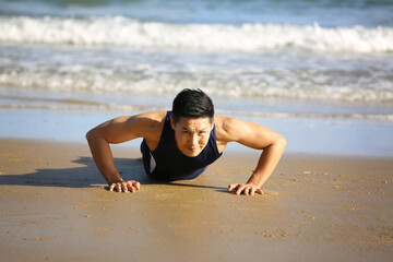 Fototapeta na wymiar Sport Men making exercises on beach in morning - fitness, sport, and lifestyle concept.