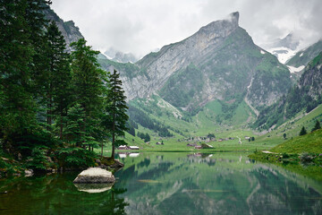 Fototapeta premium Landscape panorama from Seealpsee, Alpstein range of the canton of Appenzell, Switzerland. Green nature, mountains and their reflections on the lake.
