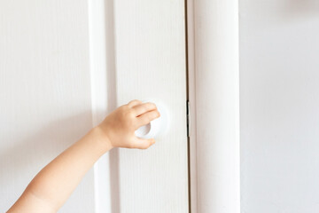 Spread of COVID-19 coronavirus by touching the door handle without antibacterial protection. The child opens the door. Or the child's hand opens the door by the handle.
