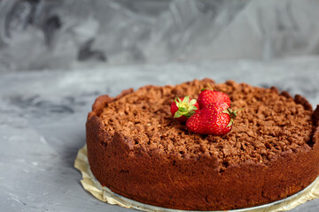 Chocolate cake is decorated with strawberry berries. Homemade cake. Pie on a grey background