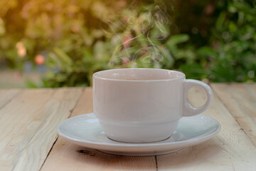 A coffee cup placed on a wooden background with a tree  bokeh