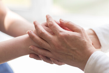 hands of an old woman touch the hands of a young girl, closeup. Psychological assistance, the doctor is a therapist, a psychologist takes the patient's hand. Give hope