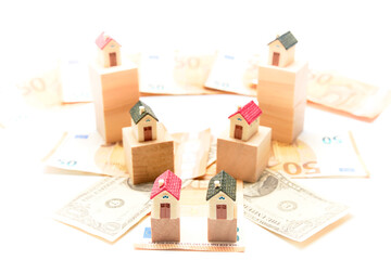 Obraz premium Miniature houses on wooden cubes and some euro and dollar bills