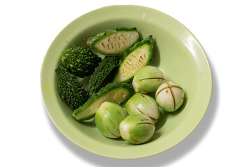Bitter gourds and green eggplants are on the green bowl isolated on white background.