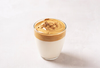 Dalgona coffee, a trendy drink. A glass of Dalgona coffee stands on a gray concrete table. Horizontal orientation, close up.