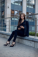 Fototapeta na wymiar Business Woman With Phone Near Office. Portrait Of Beautiful Smiling Female In Fashion Office Clothes Talking On Phone While Standing Outdoors. Phone Communication. High Quality Image.