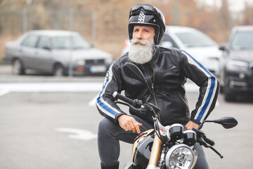 Fototapeta na wymiar Old stylish man driving the motorcycle. Brutal male.