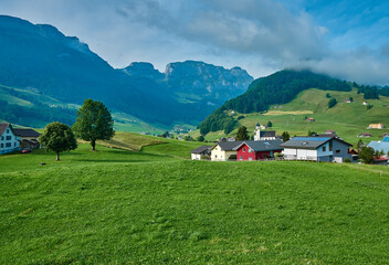 Fototapeta na wymiar Landscape panorama of green nature and village houses near Appenzell, Alpstein mountains, Switzerland. Taken in June, in summer.