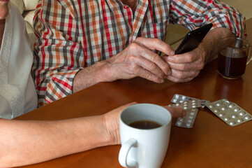 Elderly couple consulting medical questions online using the phone. Old people using technology to find information about medications.