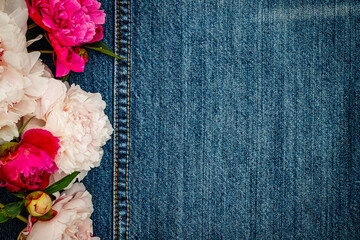 Peony flowers on denim jeans blue fabric background, closeup, copy space, text place. 