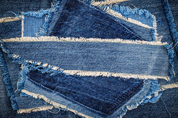 Destroyed torn denim blue jeans fabric frame on blue jeans background. Worn Jeans Casual Double...