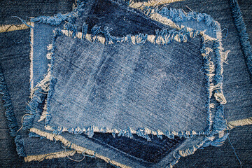 Destroyed torn denim blue jeans fabric frame on blue jeans background. Worn Jeans Casual Double...