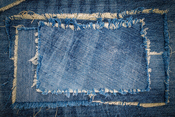 Destroyed torn denim blue jeans fabric frame on blue jeans background. Worn Jeans Casual Double Color patch Denim.