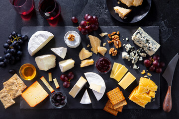 Cheese assortment on slate cutting board with red wine. Grey background. Top view.