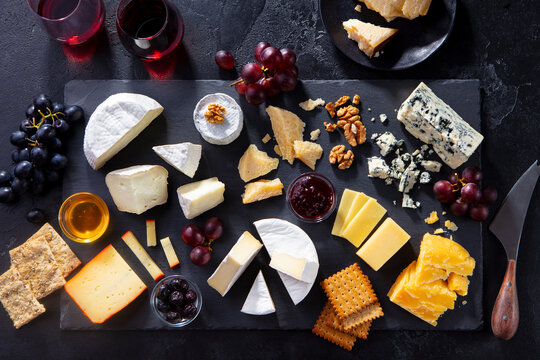 Cheese assortment on slate cutting board with red wine. Grey background. Top view.