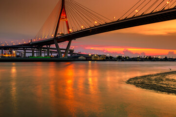 The blurred background of the twilight evening by the river, the natural color changes, the bridge over the river (Bhumibol Bridge) is one of the major transportation bridges in Bangkok, Thailand