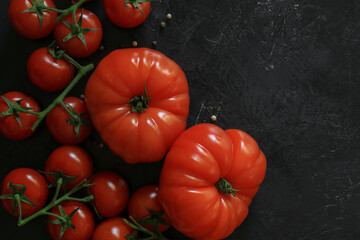 Fresh tomatoes on a black background with spices. Top view