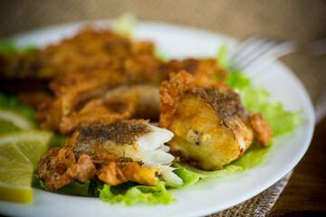 fried hake fish in batter with lettuce and lemon in a plate