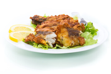 fried hake fish in batter with lettuce and lemon in a plate