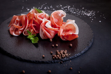 Assorted meat and allspice on a black tray of stone on a black background