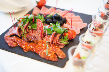 Assorted meat on a black stone tray and canapes in a restaurant