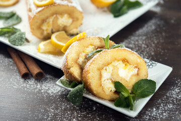 Lemon roll cake decorated with slices of lemon fruit and leaves of mint