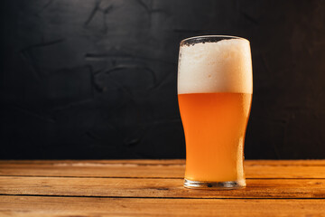 Glass of cold pale beer placed on a rustic wooden table