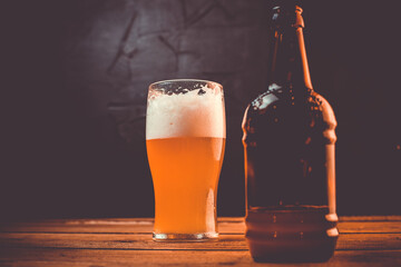 Glass of cold pale beer placed on a rustic wooden table