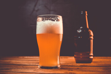 Glass of cold pale beer placed on a rustic wooden table