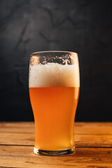 Glass of cold pale beer placed on a rustic wooden table