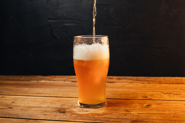 Glass of cold pale beer placed on a rustic wooden table