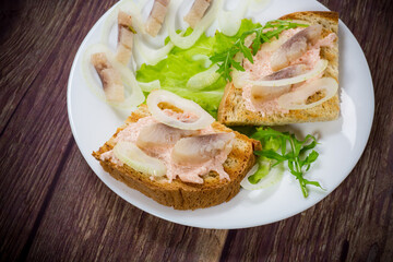 sandwich with salad, herring and herbs with onions in a plate
