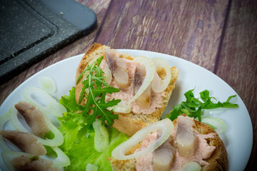 sandwich with salad, herring and herbs with onions in a plate