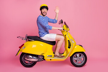 Fototapeta na wymiar Profile side view of his he nice attractive handsome cheerful cheery glad funky guy driving moped having hi hello greetings having fun isolated over pink pastel color background