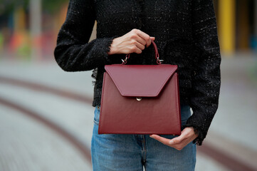 Fashionable young woman wearing blue jeans and black tweed jacket on the city street. She is...