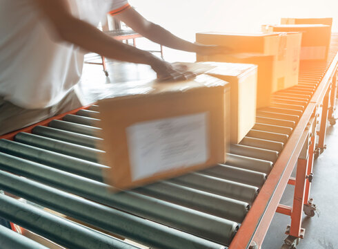 Warehouse Worker Sorting Shipment Package Boxes On Conveyor Belt In Distribution Warehouse.

