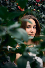 portrait of a young woman posing in leaves at the  greenhouse