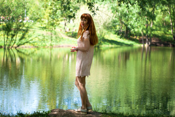 Portrait of a young beautiful woman in white dress posing by the lake