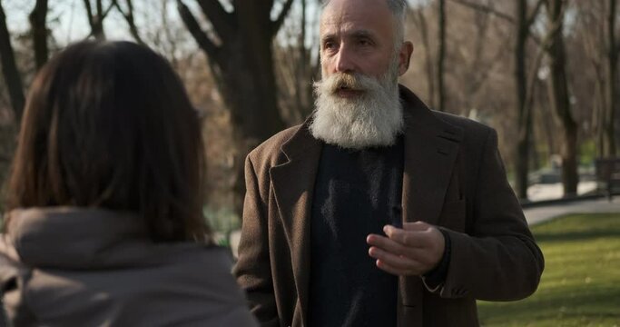 Bearded senior man talking and explaining something to woman at park