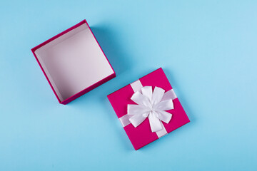 Open pink gift box on blue paper background. Top view, flat lay, place for object. Mockup, holiday concept.