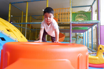 An Asian boy is enjoying playing in the playground.