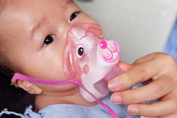 Sick boy inhalation therapy by the mask of inhaler. Boy is sick with Respiratory Syncytial Virus. Patient Boy use inhalation with Nebulizer mask at hospital. The baby are spraying bronchodilators .