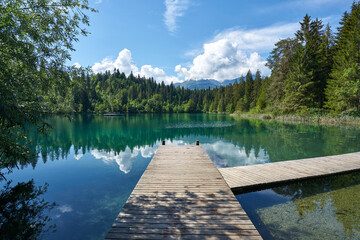 Landscape panorama of Crestasee - Lake Cresta in June, municipalities of Flims and Trin in the Grisons, Switzerland. Wooden dock on the lake.      