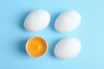 Fresh raw chicken eggs on light blue background, flat lay
