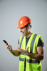 operaio con caschetto protettivo arancione e gillet giallo fa una videochiamata con il cellulare ...